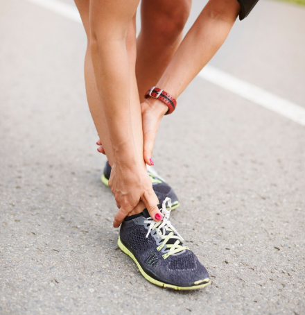 Persoon masseert enkel na hardlopen op weg