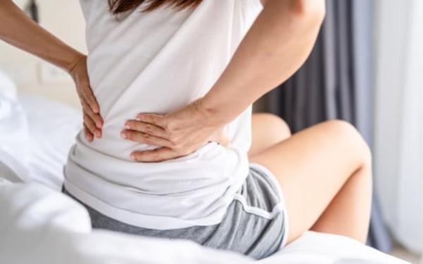 Persoon met rugpijn op bed.