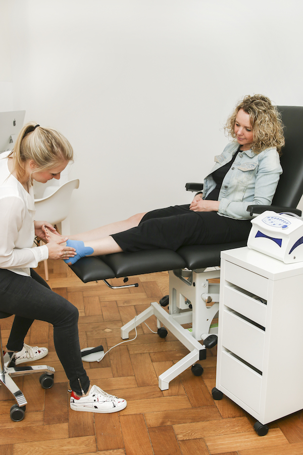 Vrouw krijgt professionele voetbehandeling in kliniek.