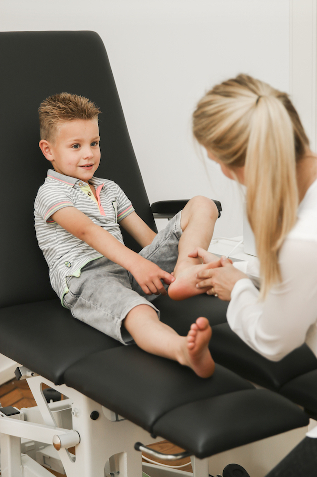 Kind met voetonderzoek door arts op behandelbank.