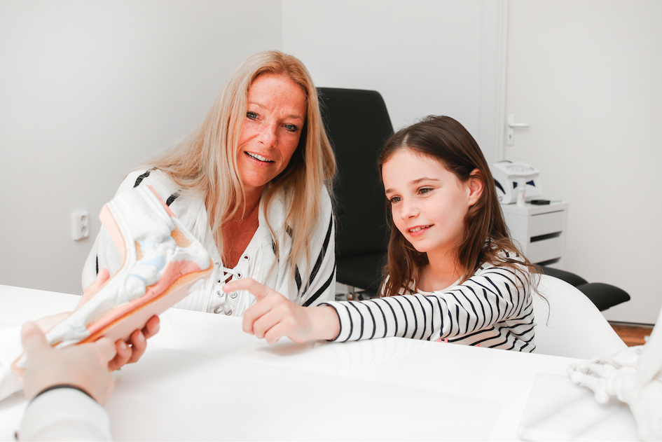 Vrouw en kind bekijken anatomisch model tijdens consult.